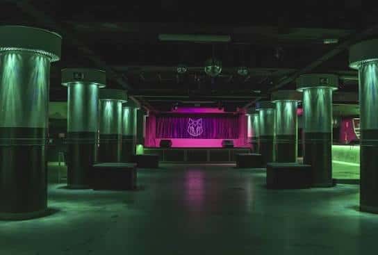 Interior del auditorio de la Sala Wolf con escenario, cortinas y columnas iluminadas