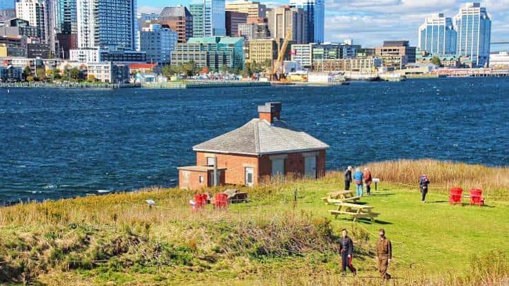 Edificio histórico de ladrillo en Georges Island con visitantes y vista panorámica de Halifax