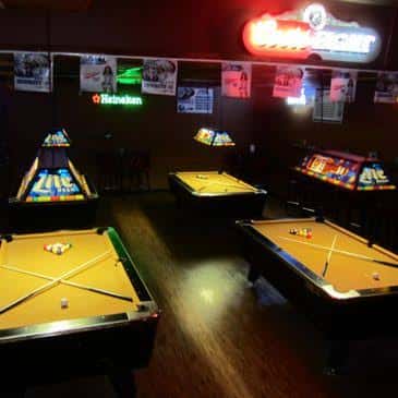 Zona de juegos con mesas de billar y máquinas arcade