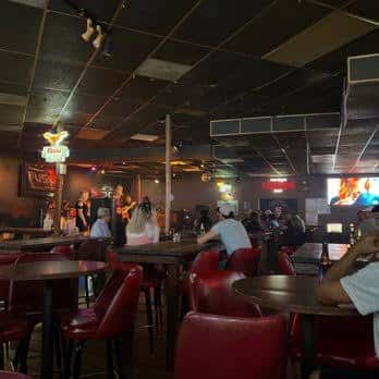 Sala de estar con mesas altas y clientes en ambiente relajado