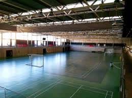 Interior del pabellón La Tejerona con pista de bádminton y estructura metálica visible