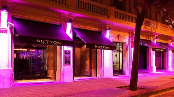 Fachada exterior del club Sutton iluminada con luces de neón