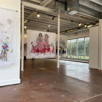 Interior de la galería con obras de arte expuestas en paredes blancas