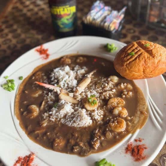 Plato de gumbo cajún con arroz y pan de maíz servido en el restaurante