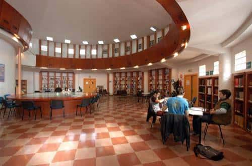 Sala de lectura circular con estanterías de madera y suelo de baldosas rojas y blancas