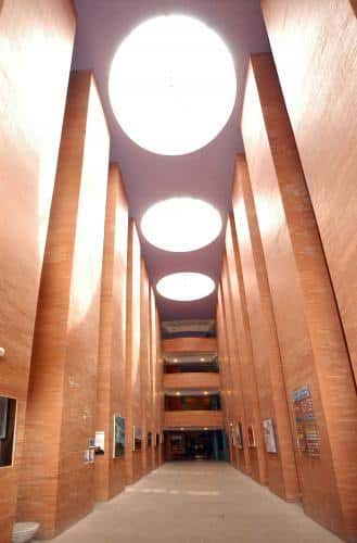 Pasillo interior con columnas de ladrillo y lucernarios circulares que iluminan el espacio