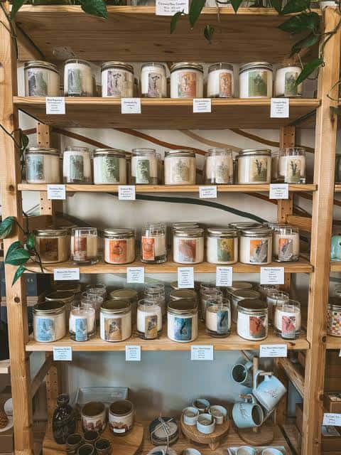 Estantería de madera con variedad de velas artesanales en frascos de vidrio
