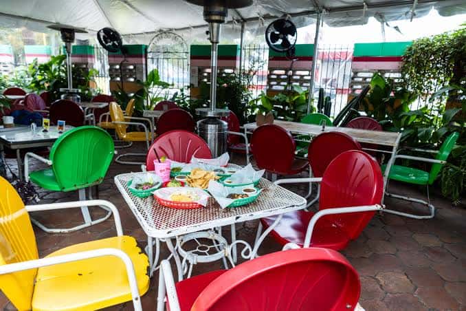Terraza al aire libre con mesas y sillas de colores vibrantes