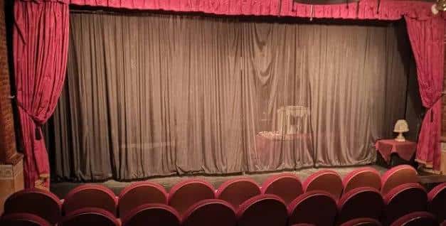 Escenario del Teatro Karpas con cortinas cerradas y butacas rojas