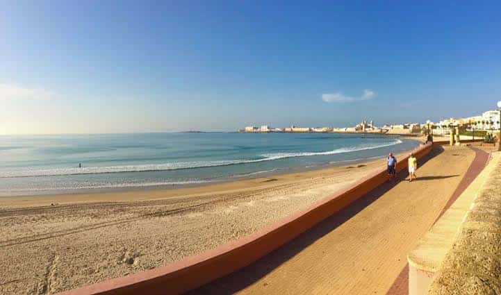 Paseo marítimo junto a la playa con el mar y la ciudad al horizonte