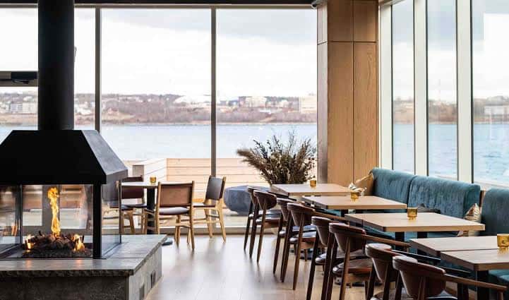 Interior de restaurante con chimenea y vistas al mar en Queen's Marque