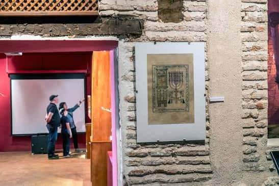 Detalle de exposición con candelabro judío y visitantes