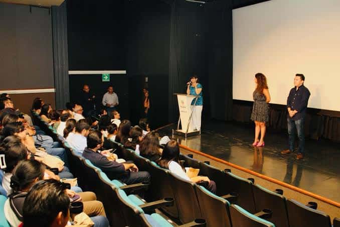 Evento en el auditorio con público y presentadores en el escenario