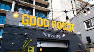 Fachada exterior de Good Robot Brewing con letrero amarillo y luces decorativas