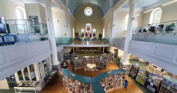 Vista interior del atrio principal de la biblioteca con estanterías curvas y balcones superiores