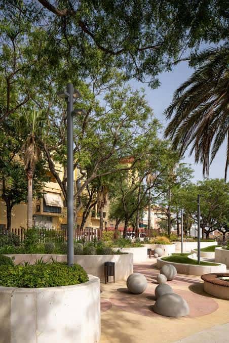 Vista general del parque con árboles frondosos y mobiliario urbano contemporáneo