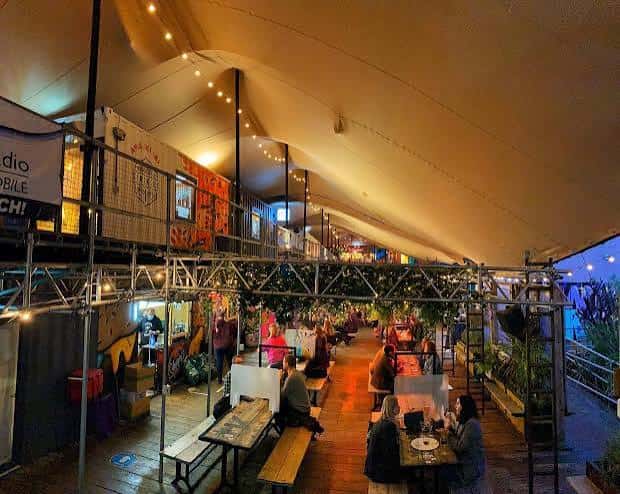 Interior del espacio Spark York con iluminación cálida y mesas de comida callejera