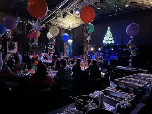 Interior del salón de eventos con mesas de invitados y decoración festiva