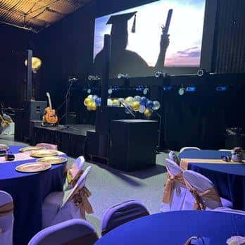 Escenario principal con pantalla de proyección y mesas preparadas para una ceremonia