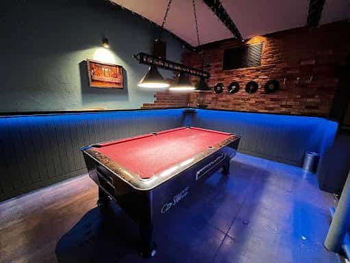 Interior del bar con mesa de billar y decoración moderna con luces azules