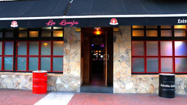 Fachada exterior del Café-Bar La Lonja con toldo negro y detalles en piedra