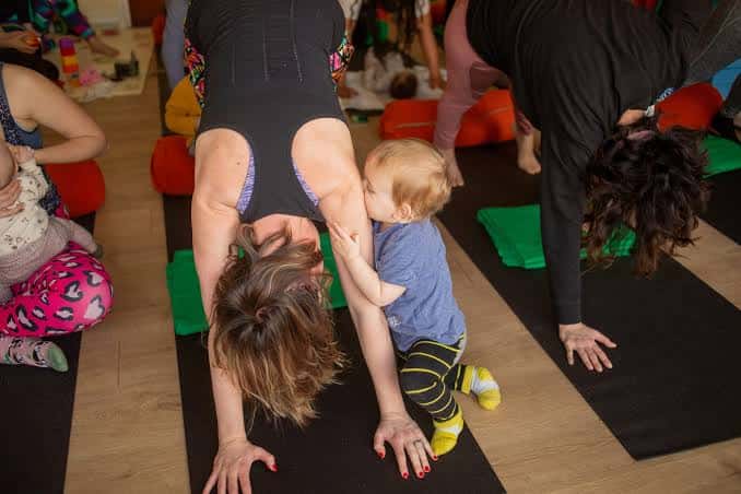 Clase de yoga familiar con bebés y adultos en sesión de estiramientos