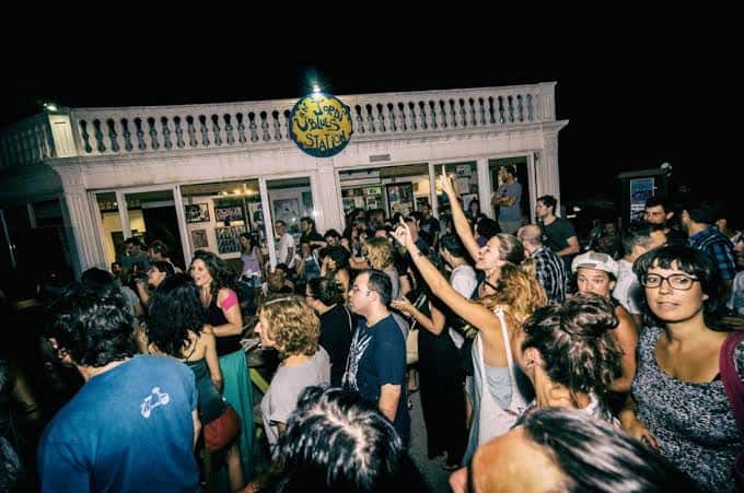 Vista nocturna de la terraza de Can Jordi Blues Station llena de gente disfrutando del ambiente