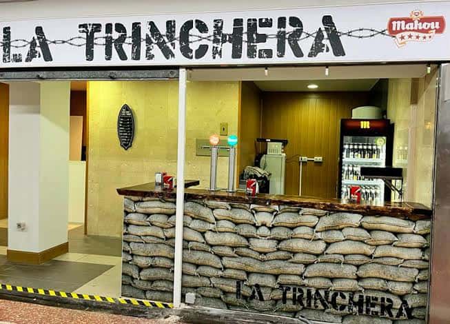Barra del local La Trinchera con decoración de sacos de arena y logo visible