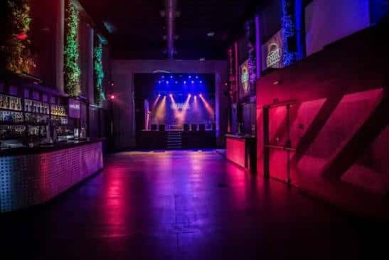 Vista nocturna del interior de Sala Villanos con iluminación de escenario y barra