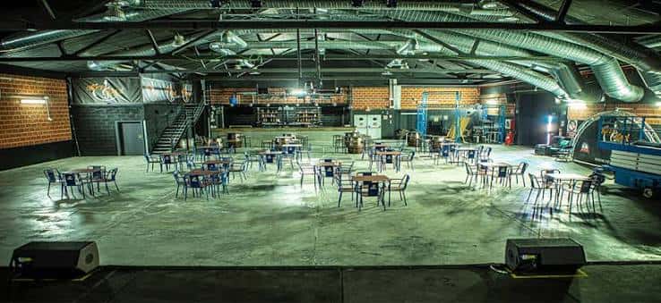 Sala de eventos industrial con mesas y sillas dispuestas para una fiesta o evento