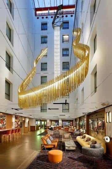 Vista del atrio principal del Hard Rock Hotel Madrid con una gran escultura dorada colgante y zona de lounge