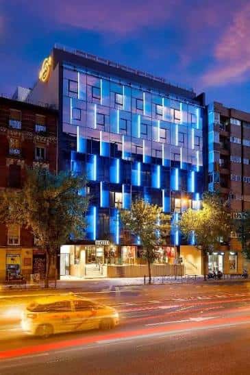 Fachada exterior del Hard Rock Hotel Madrid iluminada con luces azules durante la noche