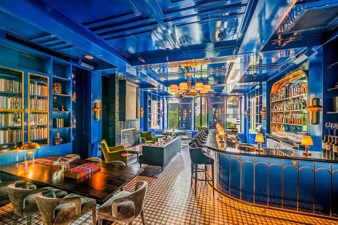 Sala azul con estanterías, sofás y barra, ideal para eventos sociales