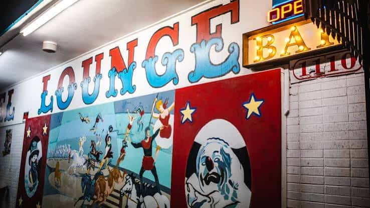 Mural de circo y letrero de neón en la pared del Carousel Lounge