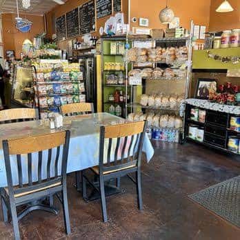 Área de venta y comedor del New World Deli con productos frescos y mesas