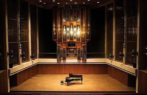 Vista del escenario del Bates Recital Hall con un piano de cola y un gran órgano en el fondo