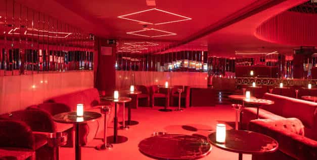 Interior del Lula Club con iluminación roja y mesas con velas