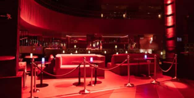 Área de lounge del Lula Club con sofás y bar en tonos rojos