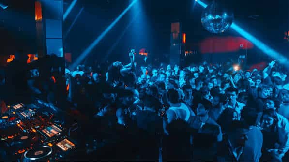 Multitud bailando bajo luces azules y un disco de luces en el Lula Club