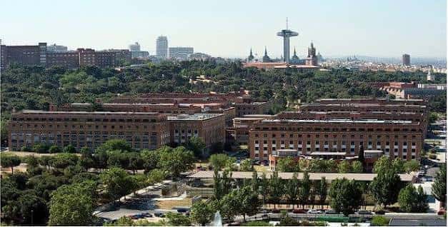Panorámica del campus universitario rodeado de zonas verdes con la torre de Madrid en el fondo