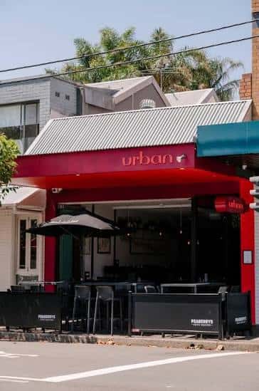 Fachada exterior del Urban Restaurant & Wine Bar con su distintivo toldo rojo y terraza al aire libre