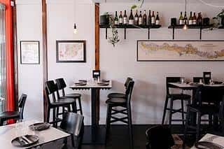Interior del restaurante con mesas dispuestas, estanterías de vino y decoración minimalista