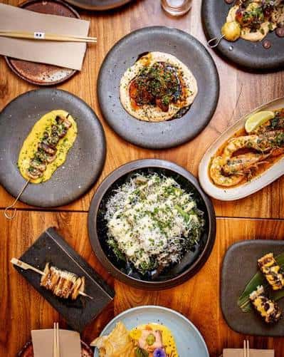 Platos de comida Nikkei presentados en mesa de madera, mostrando variedad de especialidades