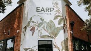 Fachada exterior de Earp Distilling Co. con mural botánico