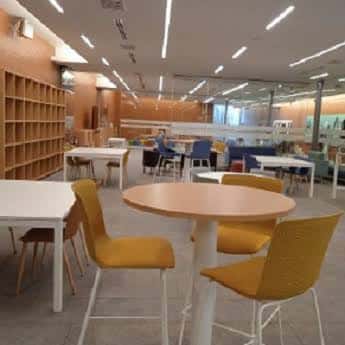 Sala de lectura y trabajo con mesas modernas y estanterías de madera