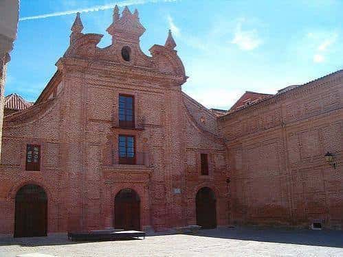 Vista frontal de la Plaza de San Agustín bajo cielo azul, destacando su fachada de ladrillo y detalles ornamentales