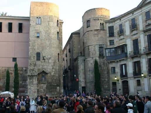 Vista de la Plaça Nova con la Torre de les Aigües y la Torre de la Corona, mostrando la arquitectura medieval y la multitud de visitantes