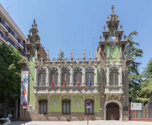Vista frontal del edificio histórico de la plaza con arquitectura detallada y banderas en fachada