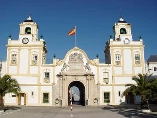 Fachada principal del Arsenal de la Carraca bajo un cielo azul despejado, mostrando su arquitectura neoclásica