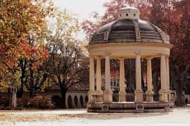 Gazebo neoclásico con cúpula y columnas rodeado de árboles con follaje otoñal